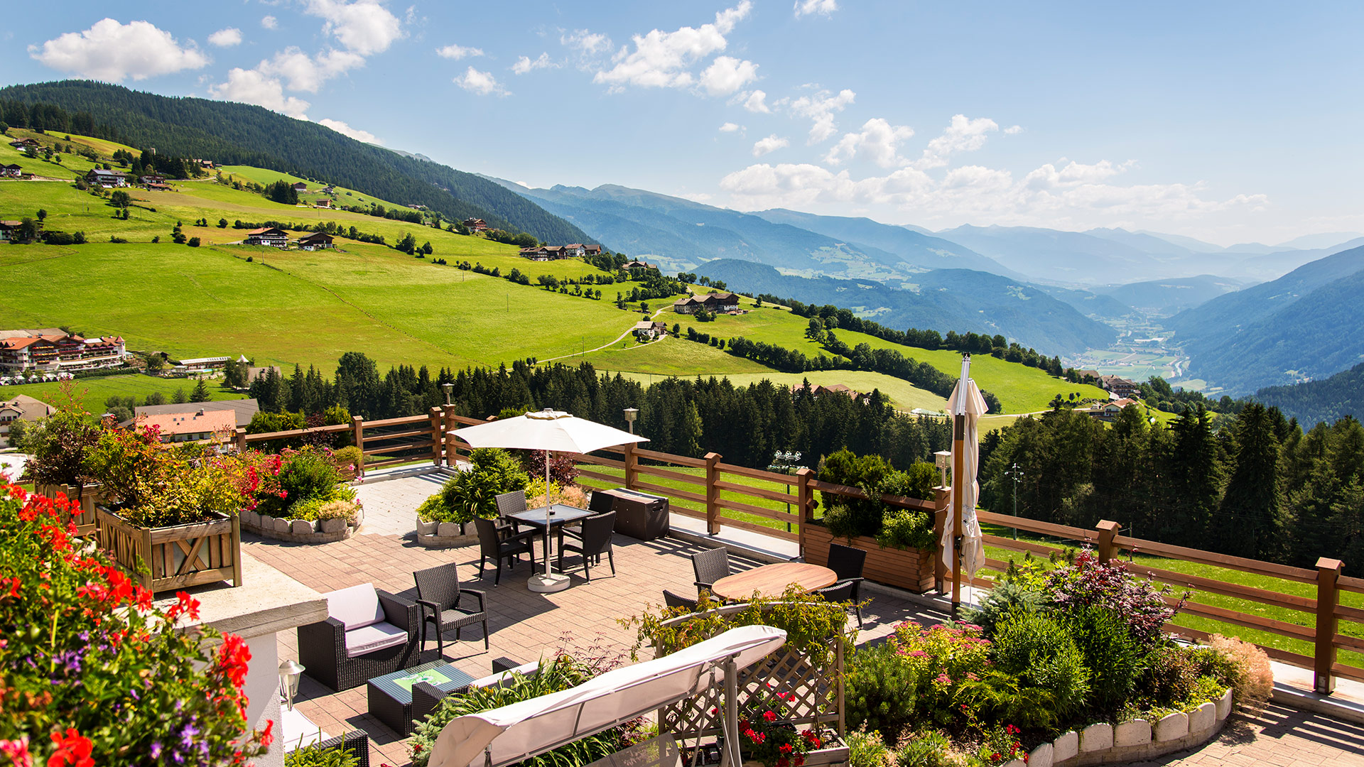 Blühende Terrasse der Pension Wiesenrain mit spektakulärem Blick auf die grünen Berge des Pustertals, in Meransen.