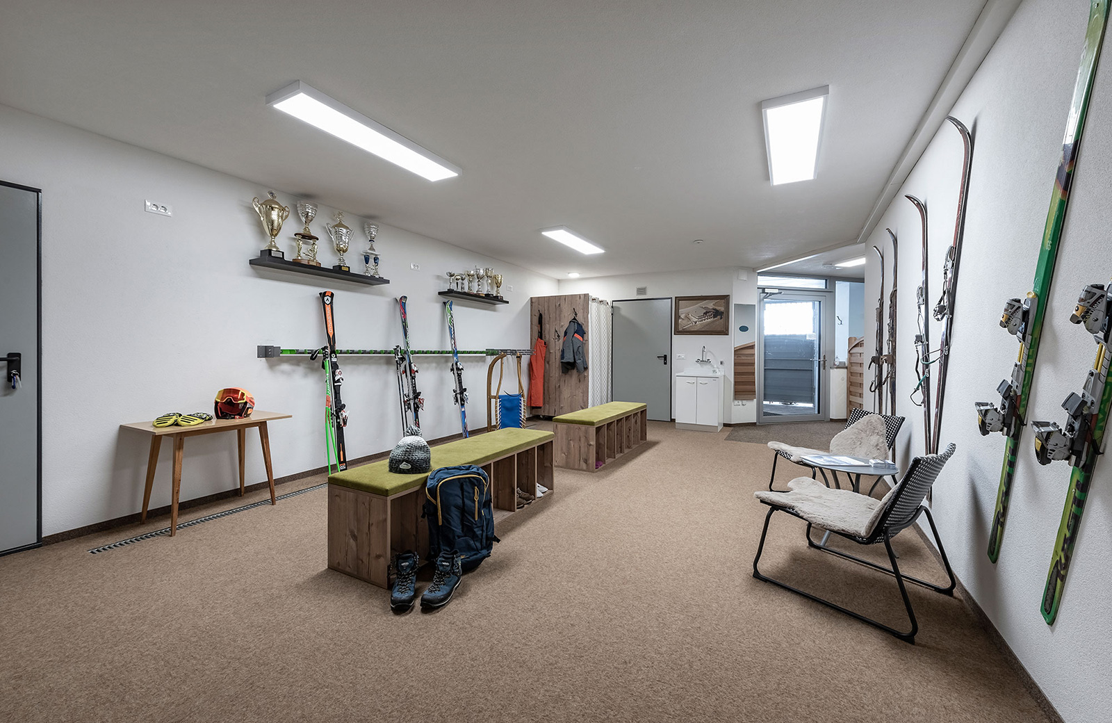 The spacious and well-equipped ski storage room of Pension Wiesenrain, with ski racks, benches, and trophies.