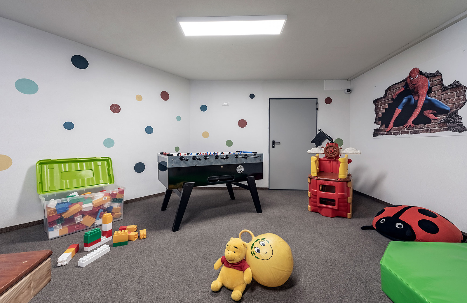 Bright playroom at Pension Wiesenrain with foosball, building blocks, Winnie the Pooh and Spiderman plush toys on the wall, ideal for families in Maranza.