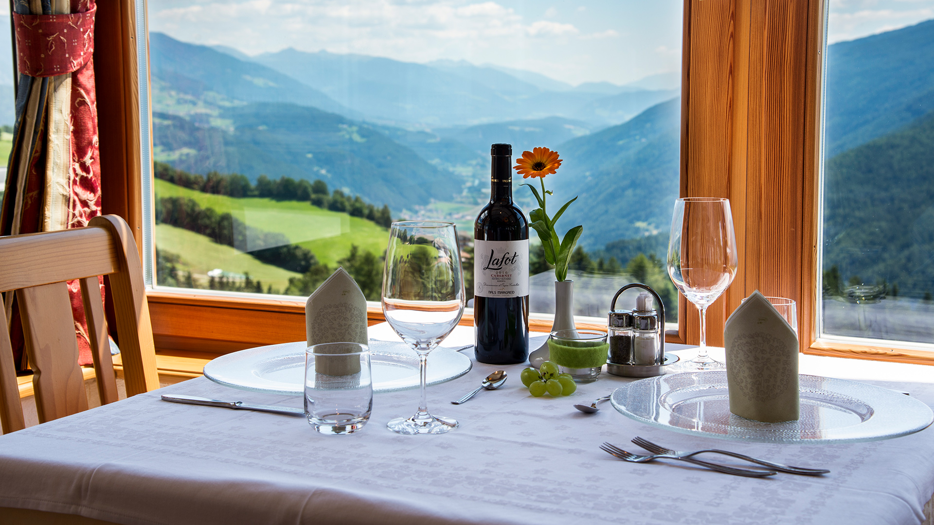 Gedeckter Tisch im Panorama-Speisesaal der Pensione Wiesenrain mit Blick auf die Dolomiten und das Pustertal.
