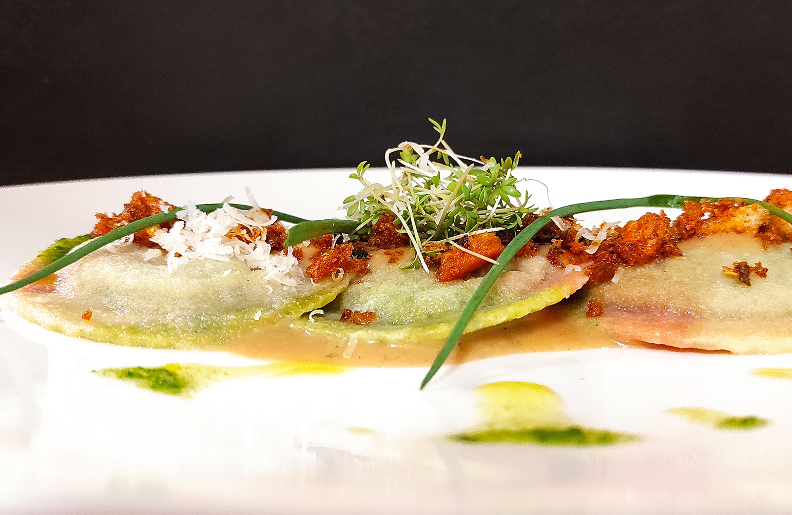 Hausgemachte grüne Ravioli mit knusprigem Guanciale, Käsesplittern und frischen Sprossen, ein saisonales Gericht der Pension Wiesenrain in Südtirol.