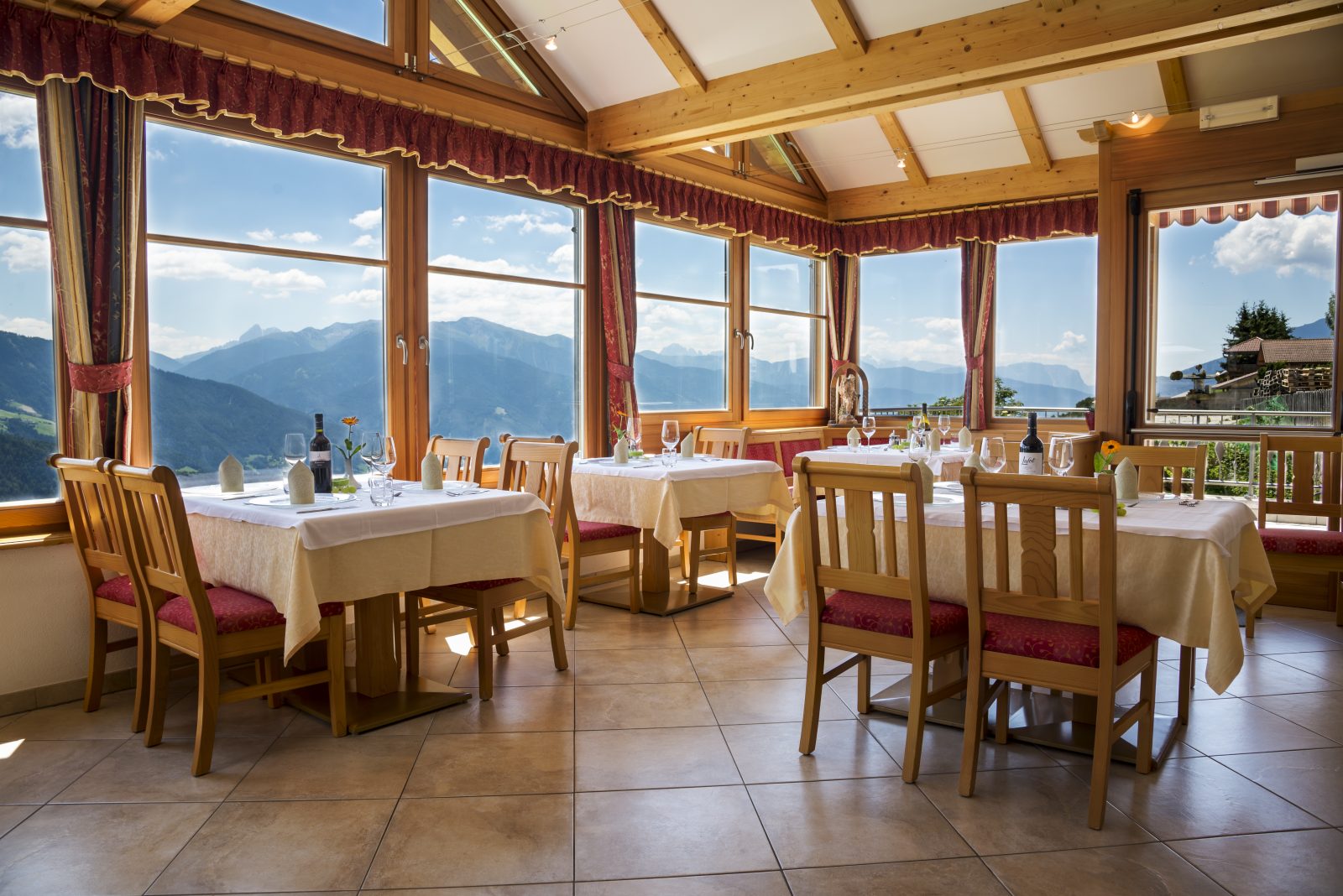 Speisesaal der Pension Wiesenrain mit gedeckten Tischen und Panoramablick auf die Dolomiten.