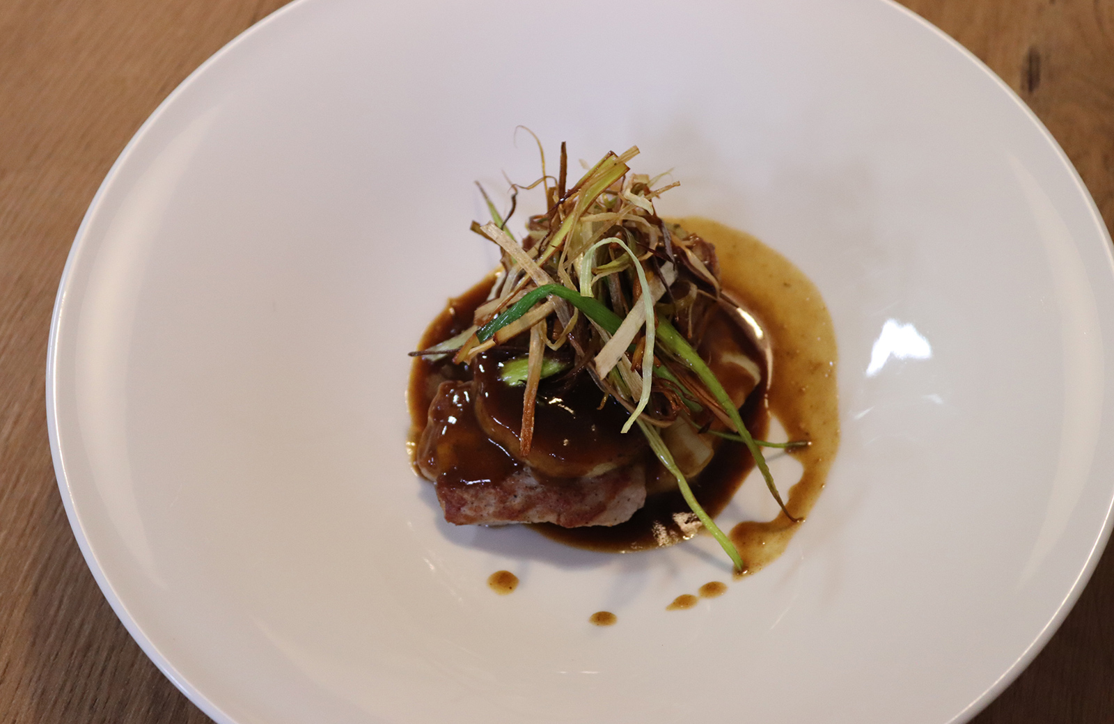 Ein Gourmetgericht aus der Küche der Pension Wiesenrain, mit Fleisch, dunkler Soße und Kräuter garniert.