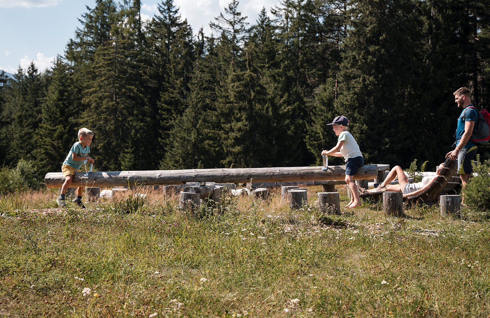 Family on holiday in Maranza: Two children play on a wooden beam, while the parents relax.