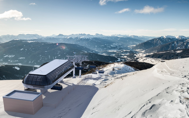 Top station of the new chairlift in the Gitschberg Jochtal ski area, with snow-covered slopes and a view of the Dolomites.
