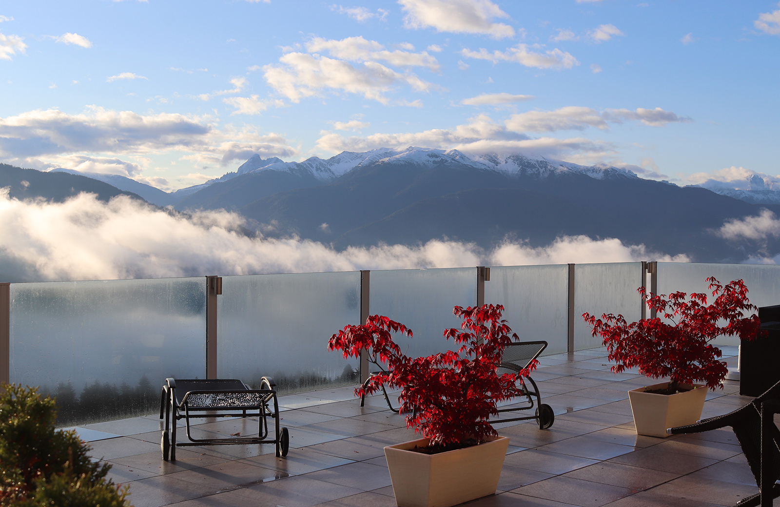 Terrace of Pension Wiesenrain with a spectacular view of the snow-covered Dolomites and the Pusteria Valley enveloped in clouds.